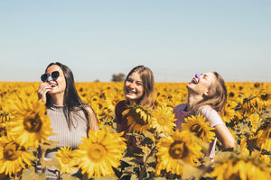 Mother and two daughters in a field of sun flowers with neon suntan lotion on their noses